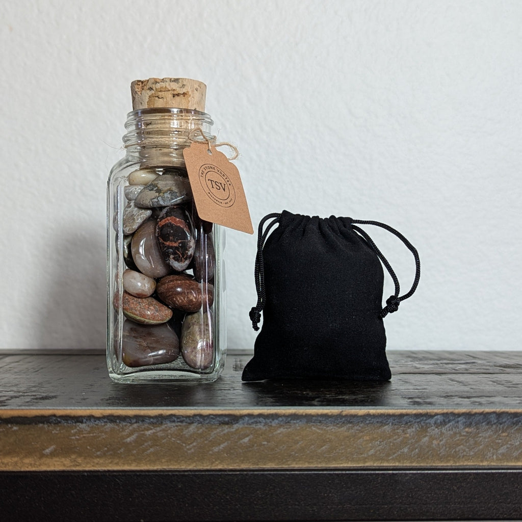 Glass jar with cork lid and black drawstring bag on a wooden surface.