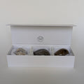 Open white box containing three stones on a light gray background
