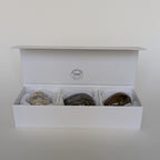 Open white box containing three stones on a light gray background