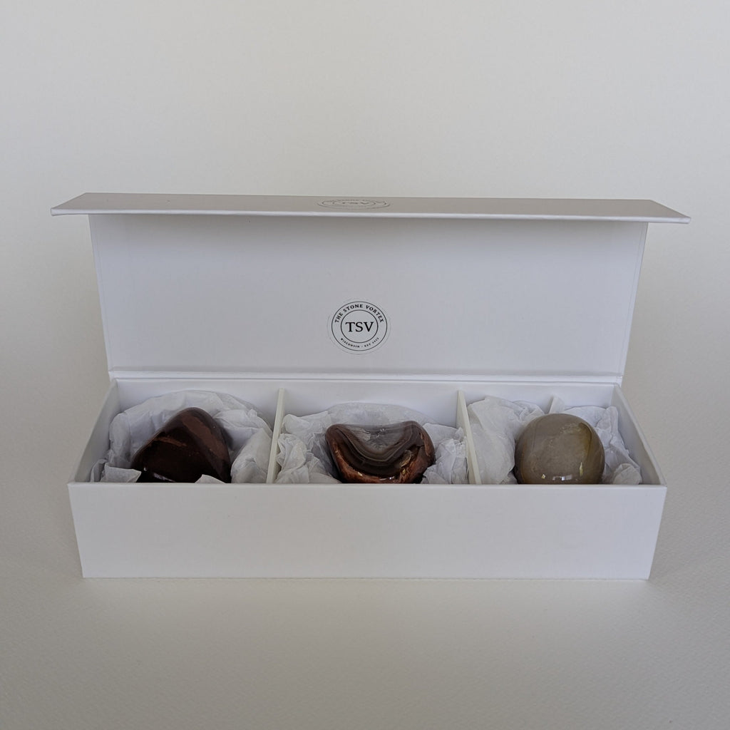 White jewelry box with three stones including a lake superior agate inside on a white background